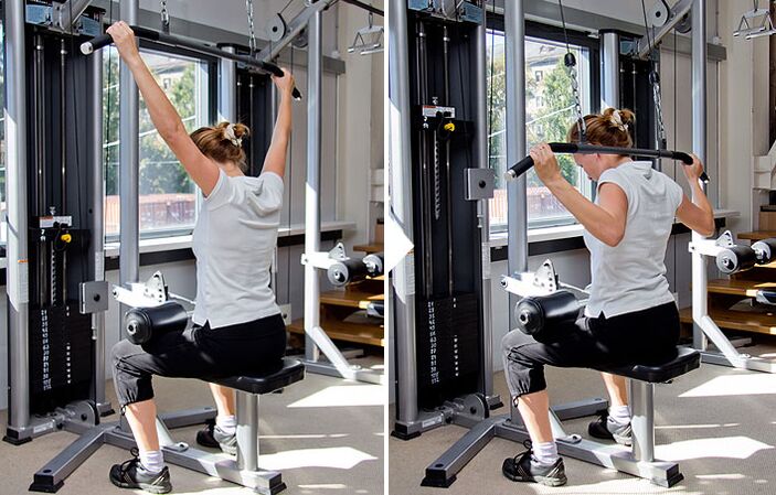 Narik blok tukangeun tukang dina simulator mantuan pikeun ngerjakeun otot latissimus dorsi